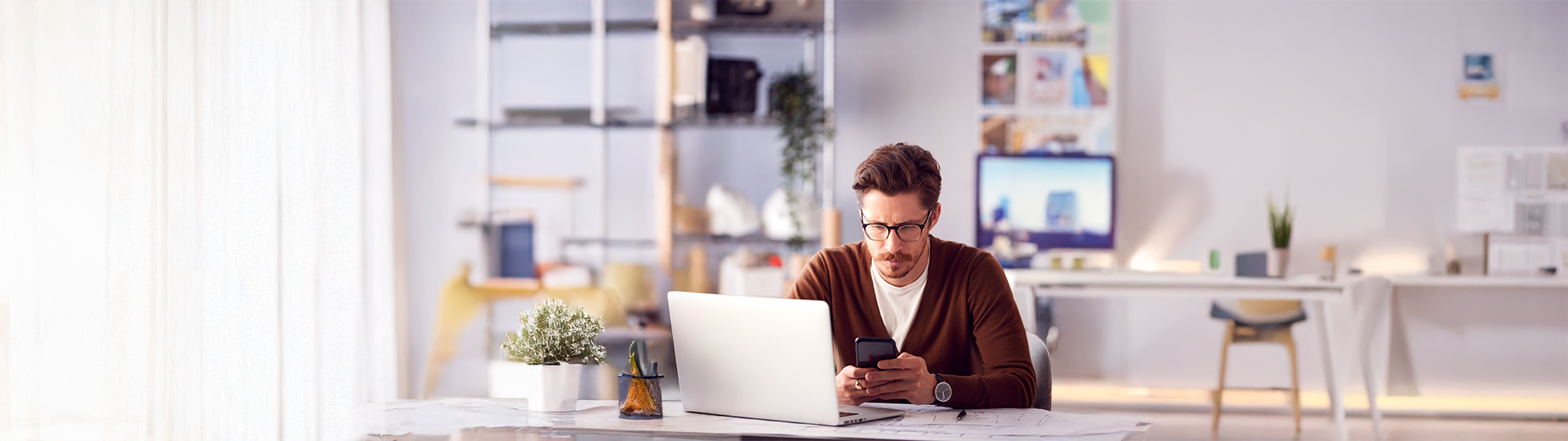 Profissional em escritório usando notebook e celular corporativos, dispositivos que entram no ciclo de ITAD para empresas